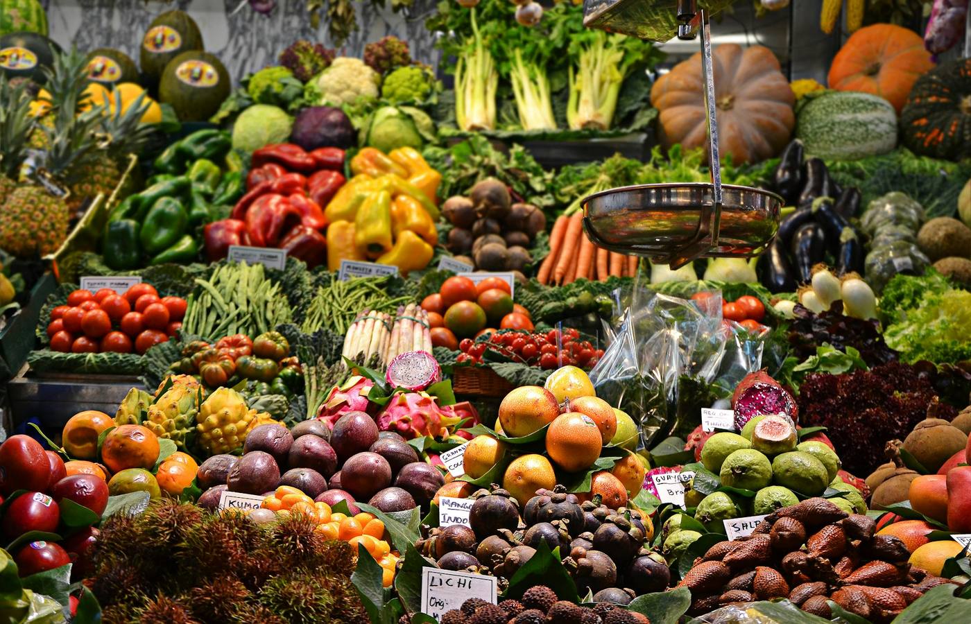 A stall at a central produce market, cases of vegetables stacked to the ceiling